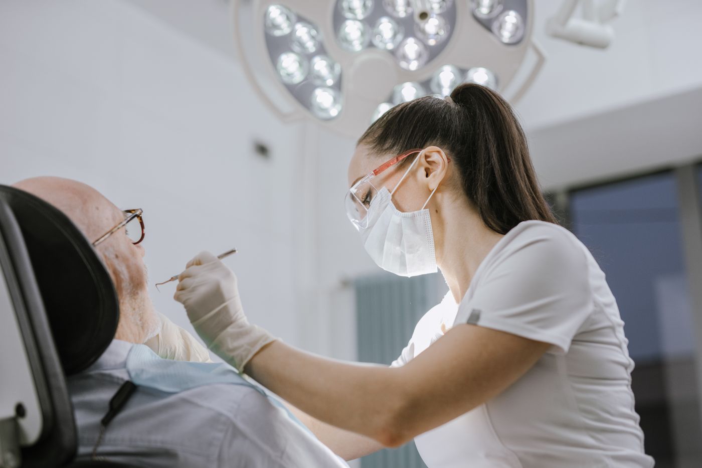 A dental team member examines a patient under bright light