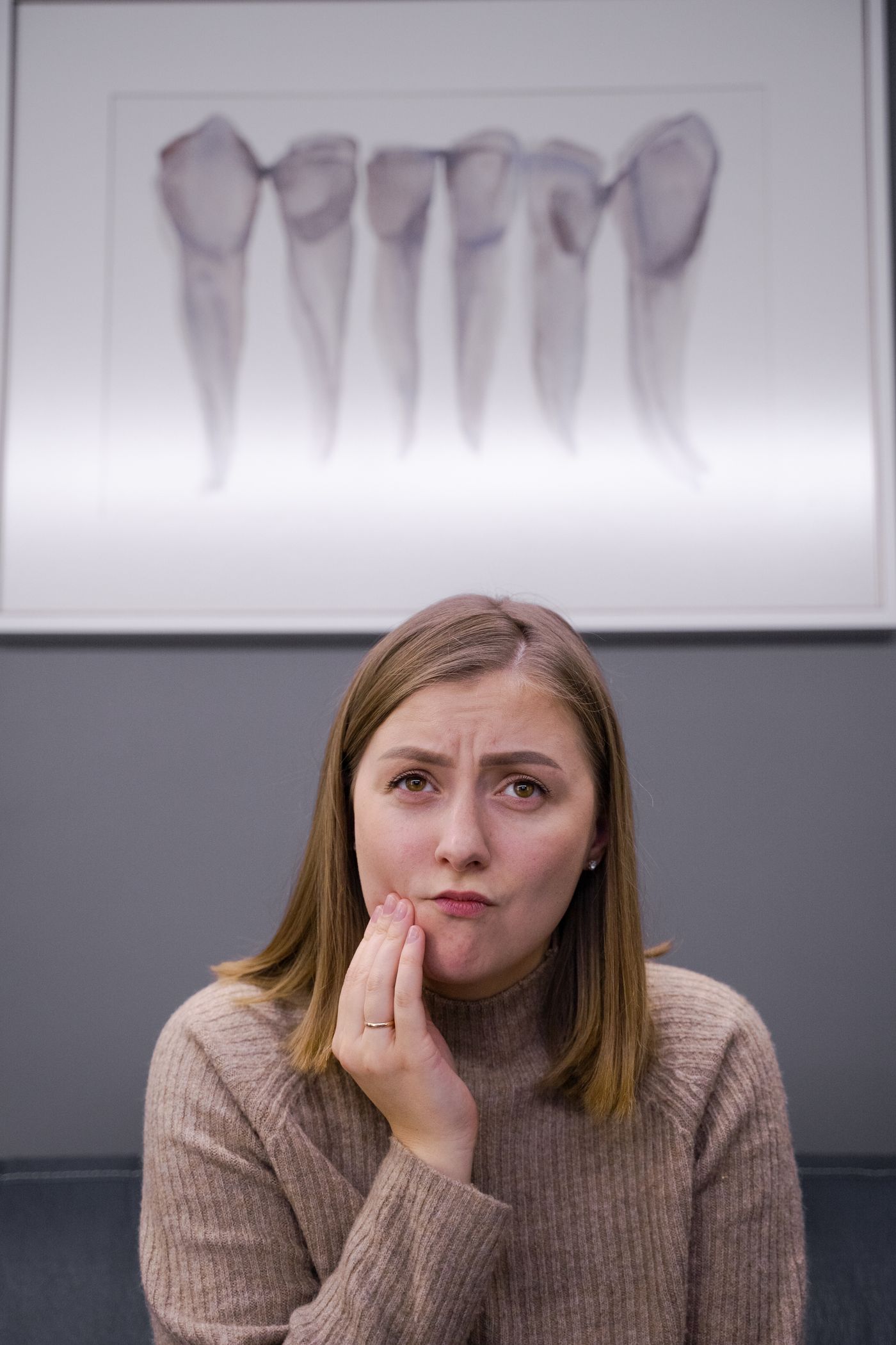 A woman with her hand on her cheek, feeling tooth pain