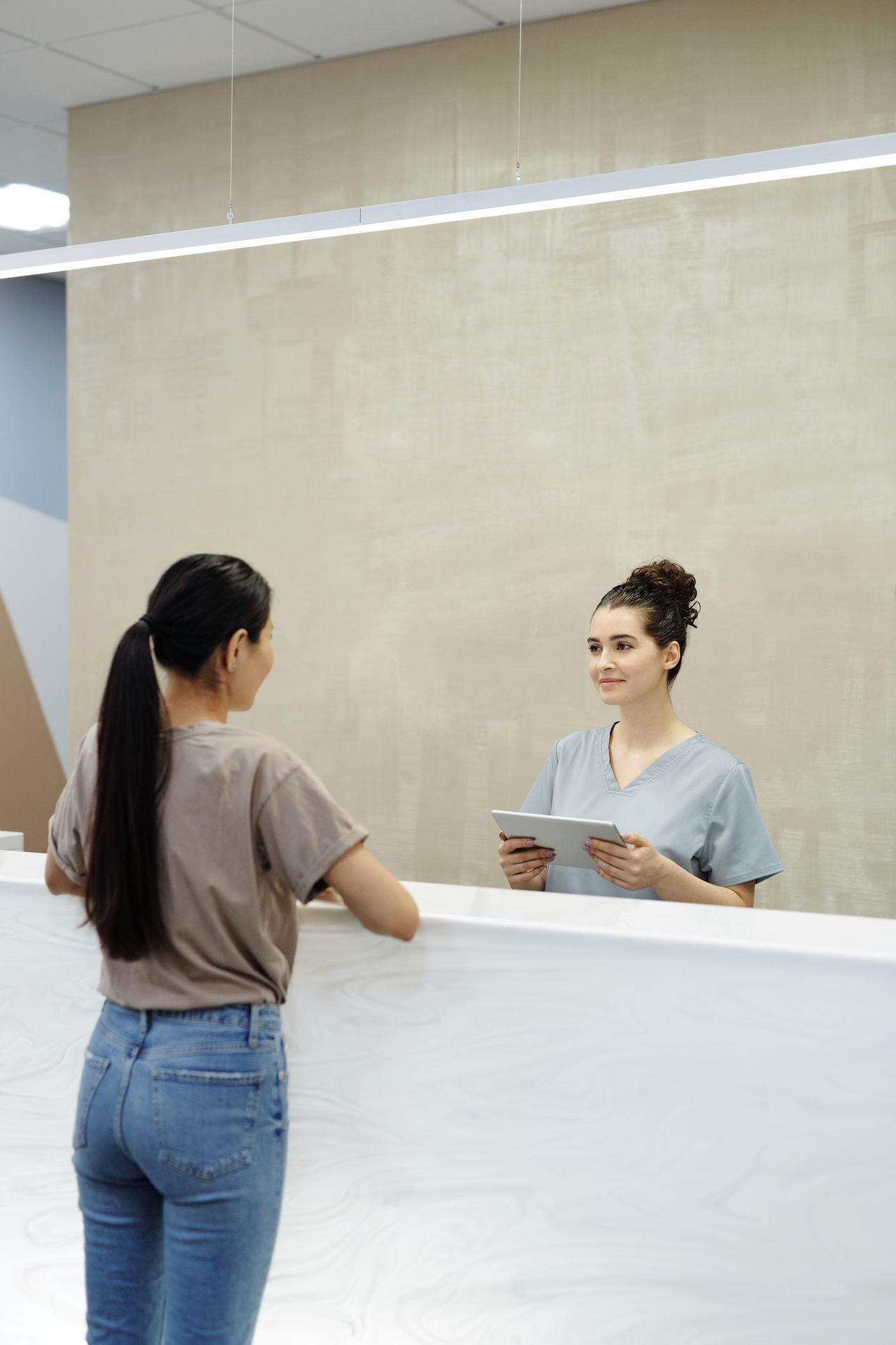 A patient speaks with a team member at the front desk of a dental office