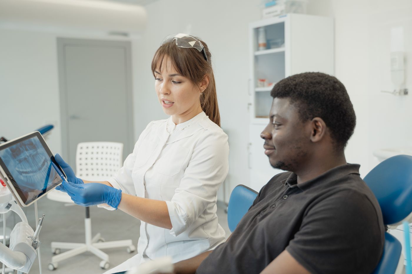 A dentist explains an X-ray on a tablet to a patient